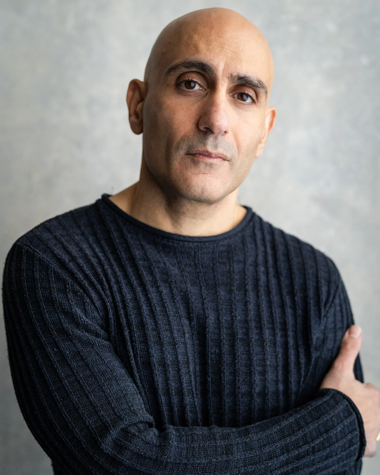 Chris Nicou, arms crossed, dark knit jumper